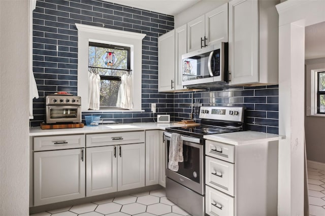 kitchen with stainless steel appliances, tasteful backsplash, plenty of natural light, and white cabinetry