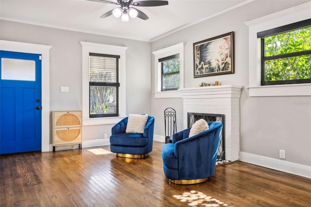 sitting room with ornamental molding, dark wood-type flooring, ceiling fan, and a fireplace