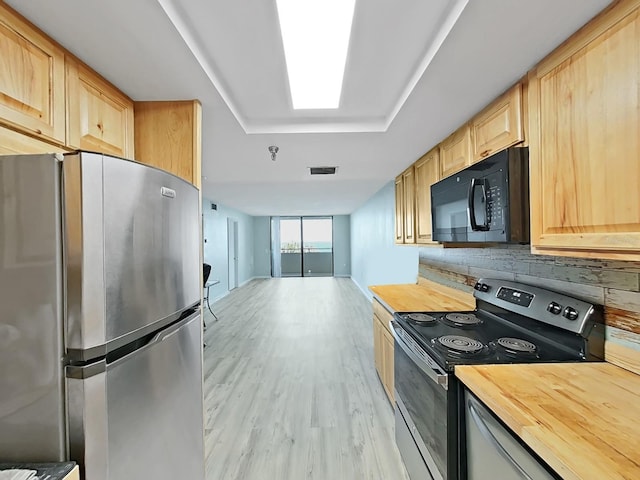 kitchen featuring a skylight, stainless steel appliances, visible vents, light brown cabinets, and wood counters