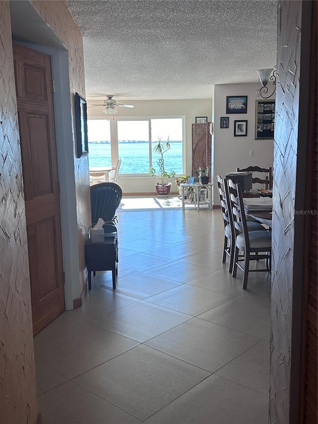 corridor featuring tile patterned flooring, a textured ceiling, and a water view