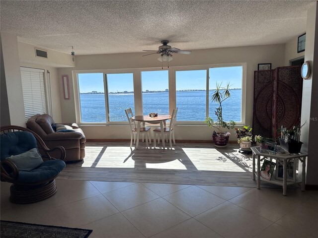 sunroom with a water view and ceiling fan