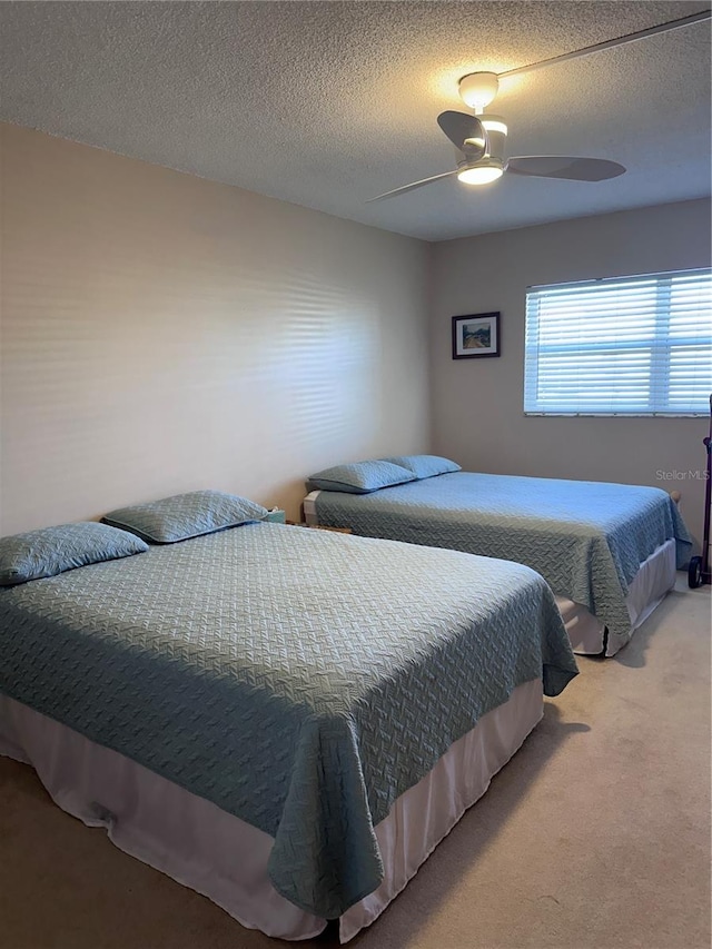 bedroom featuring ceiling fan, carpet floors, and a textured ceiling