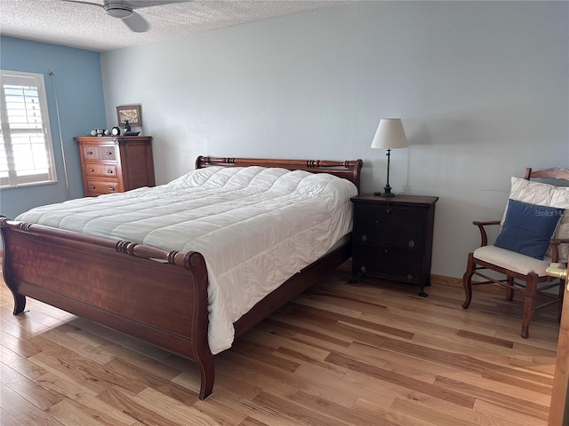 bedroom with a textured ceiling, light hardwood / wood-style flooring, and ceiling fan