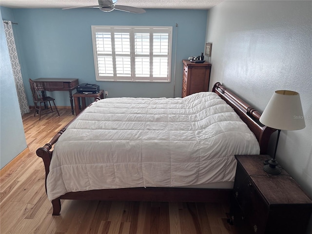 bedroom featuring ceiling fan, light hardwood / wood-style floors, and a textured ceiling