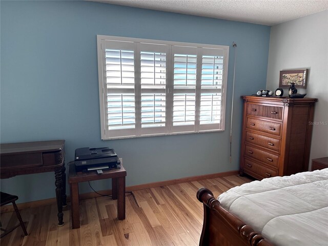 bedroom with a textured ceiling and light hardwood / wood-style floors