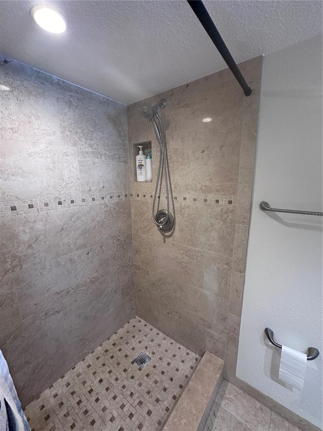 bathroom featuring tile patterned floors, a textured ceiling, and tiled shower