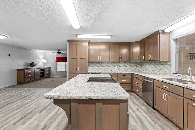 kitchen featuring dishwasher, sink, a textured ceiling, a kitchen island, and light wood-type flooring