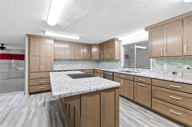 kitchen featuring light wood-type flooring, a textured ceiling, sink, dishwasher, and a kitchen island