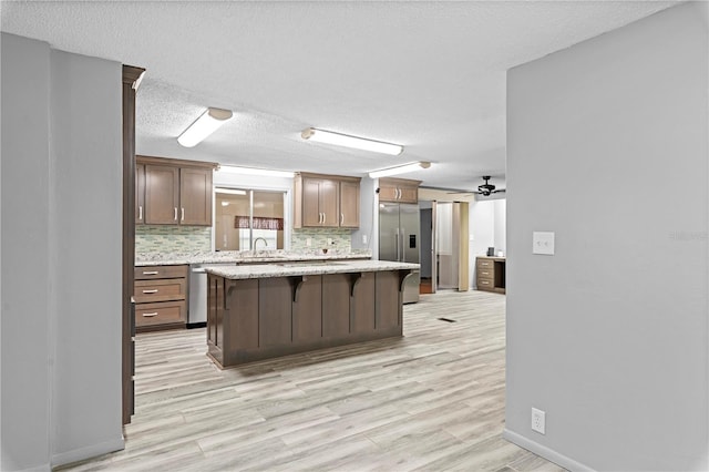 kitchen featuring a breakfast bar area, ceiling fan, a kitchen island, and light hardwood / wood-style floors