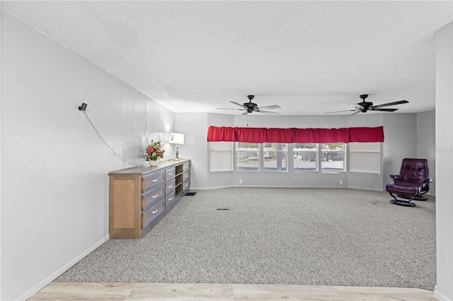 unfurnished living room featuring carpet flooring, ceiling fan, and a textured ceiling