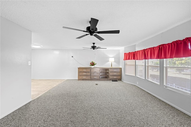 empty room featuring ceiling fan, carpet floors, and a textured ceiling