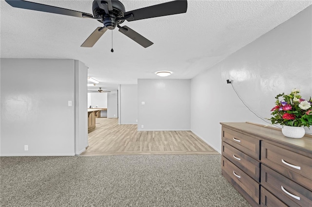 unfurnished living room with a textured ceiling, light hardwood / wood-style flooring, and ceiling fan