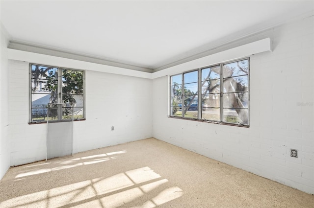 carpeted empty room featuring brick wall