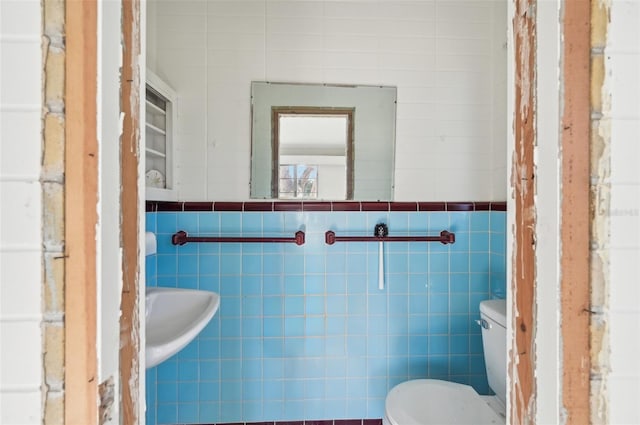 bathroom featuring toilet and tile walls