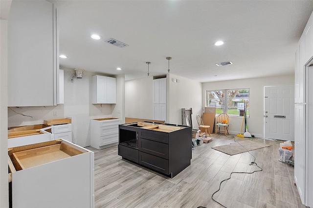 4145 Harrisburg St NE, Saint Petersburg, FL 33703 - kitchen featuring white cabinetry, dark cabinets, light wood finished floors, recessed lighting, and a center island