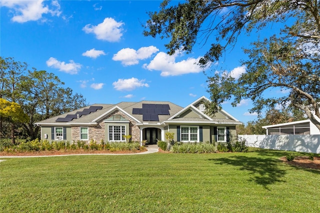 view of front of home with a front yard and solar panels