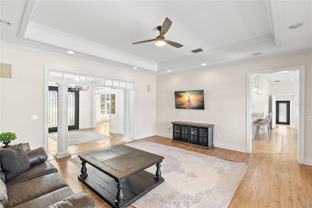 living room with decorative columns, ornamental molding, a raised ceiling, ceiling fan, and light hardwood / wood-style flooring