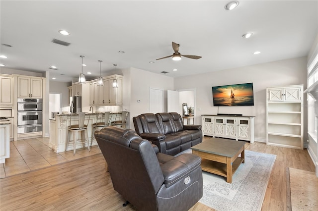 living room featuring ceiling fan and light hardwood / wood-style floors