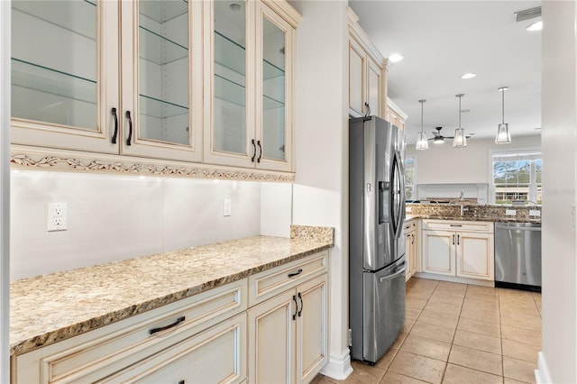 kitchen with appliances with stainless steel finishes, light stone counters, light tile patterned floors, pendant lighting, and cream cabinetry