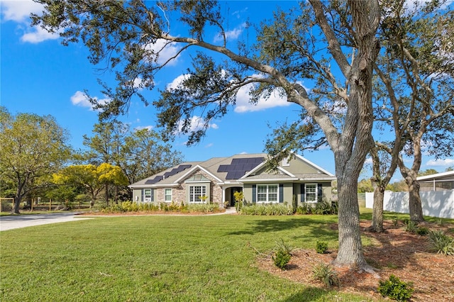 ranch-style house featuring a front yard and solar panels