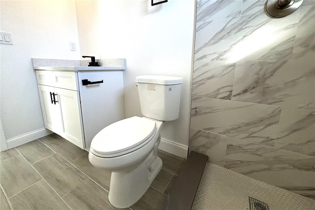 bathroom with a tile shower, vanity, and toilet