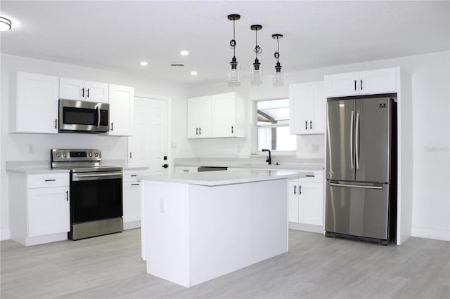 kitchen featuring pendant lighting, a center island, appliances with stainless steel finishes, light hardwood / wood-style floors, and white cabinetry