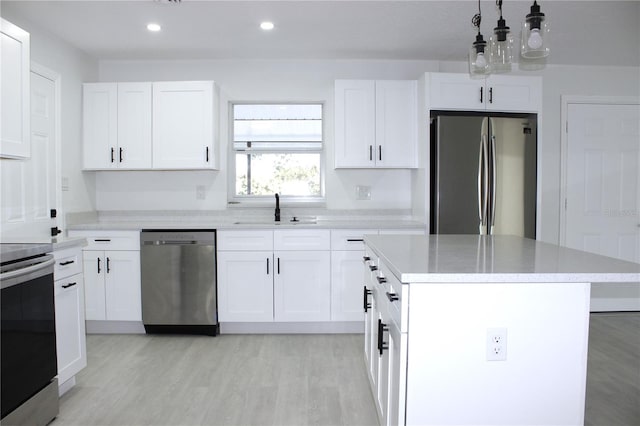 kitchen featuring white cabinetry, sink, stainless steel appliances, light hardwood / wood-style flooring, and a kitchen island