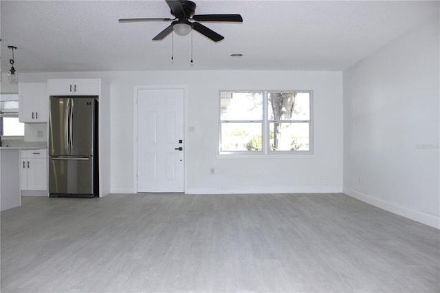 unfurnished living room with a textured ceiling, light hardwood / wood-style floors, and ceiling fan