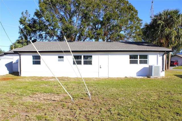 rear view of property with central AC unit and a lawn