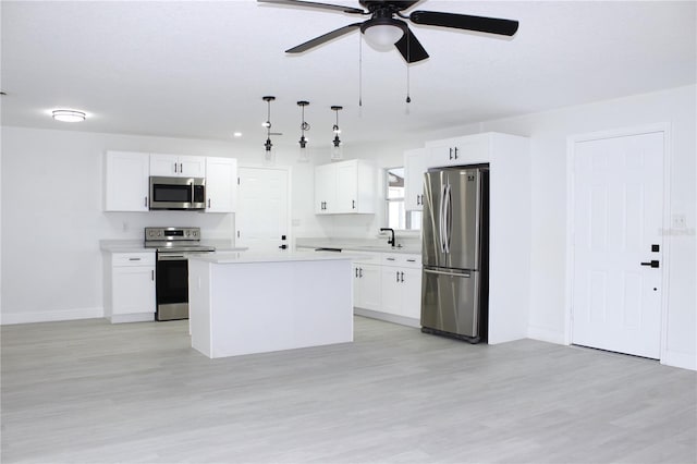 kitchen with a center island, hanging light fixtures, ceiling fan, appliances with stainless steel finishes, and white cabinetry