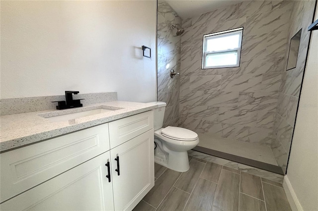 bathroom with tiled shower, vanity, and toilet