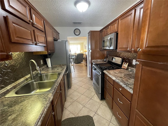 kitchen featuring light tile patterned flooring, tasteful backsplash, sink, dark stone counters, and stainless steel appliances