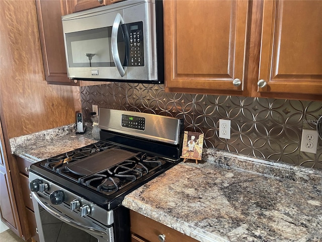 kitchen with tasteful backsplash, appliances with stainless steel finishes, and stone counters