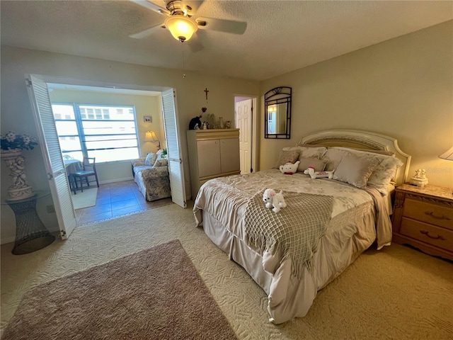 bedroom with a textured ceiling, ceiling fan, and light carpet