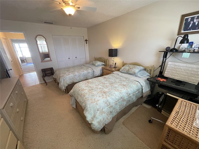 carpeted bedroom with ceiling fan, a closet, and a textured ceiling