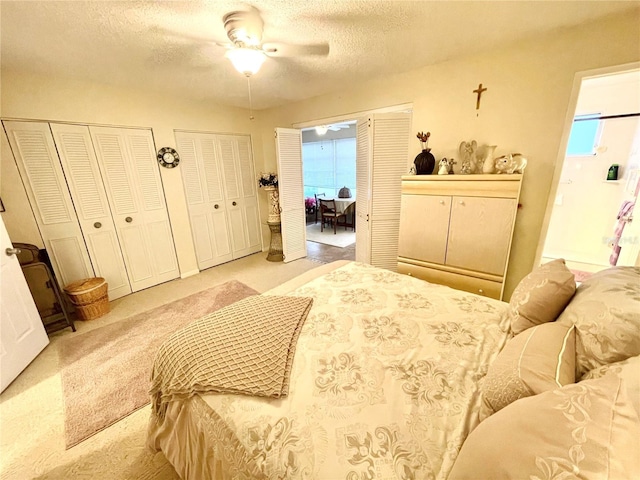 carpeted bedroom with multiple closets, a textured ceiling, and ceiling fan