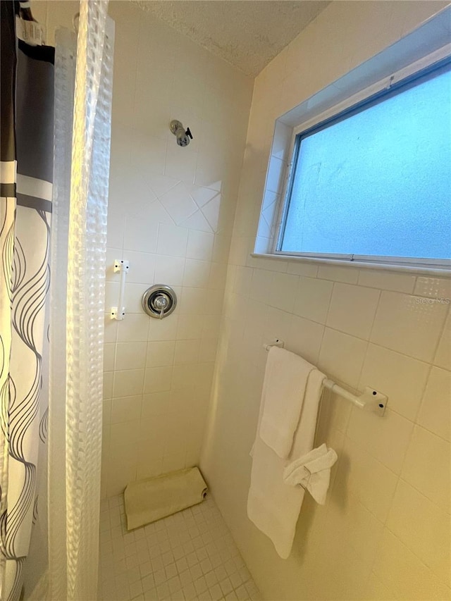 bathroom featuring tile patterned flooring, tile walls, a textured ceiling, and a shower with curtain