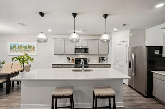 kitchen with appliances with stainless steel finishes, pendant lighting, gray cabinetry, and sink