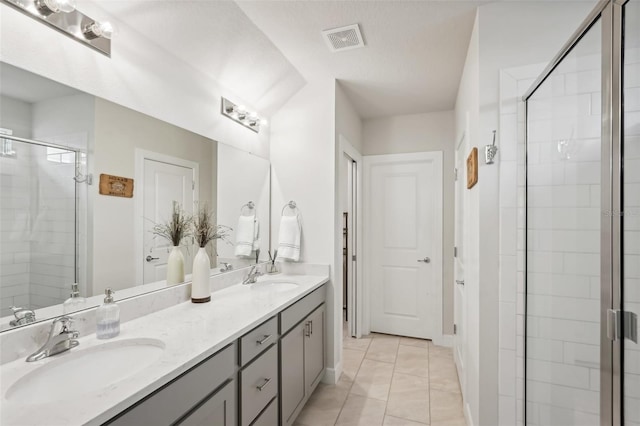 bathroom featuring tile patterned flooring, vanity, a shower with door, and a textured ceiling