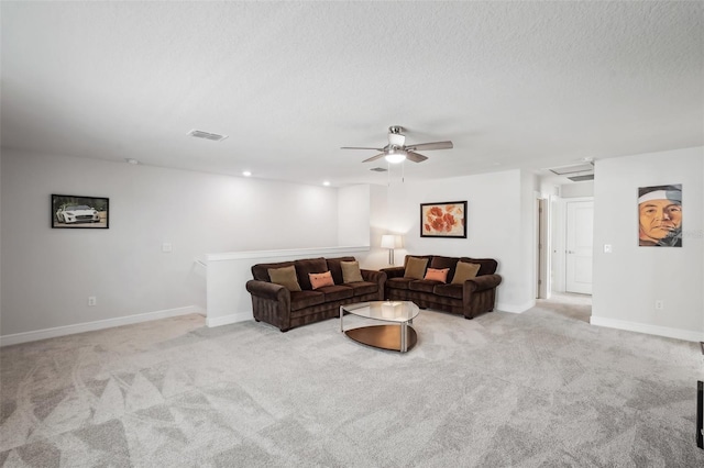 living room featuring a textured ceiling, ceiling fan, and light carpet