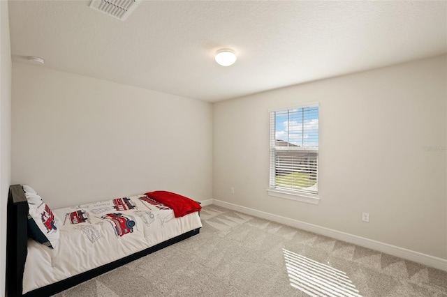 bedroom with a textured ceiling and light carpet