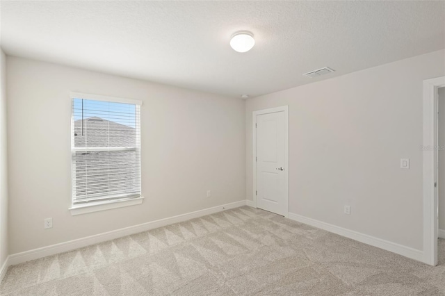 unfurnished room with a textured ceiling and light carpet