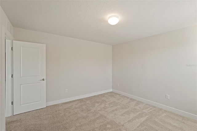 unfurnished room with a textured ceiling and light carpet