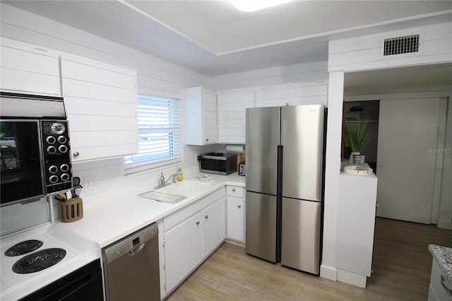 kitchen featuring white cabinets, sink, a textured ceiling, appliances with stainless steel finishes, and light hardwood / wood-style floors