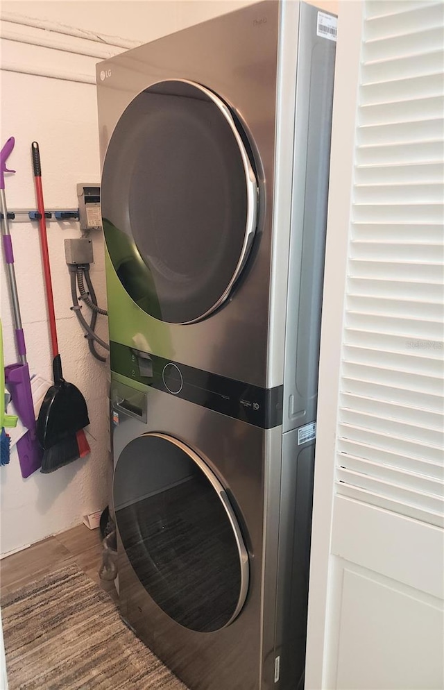 laundry room featuring hardwood / wood-style floors and stacked washer and dryer