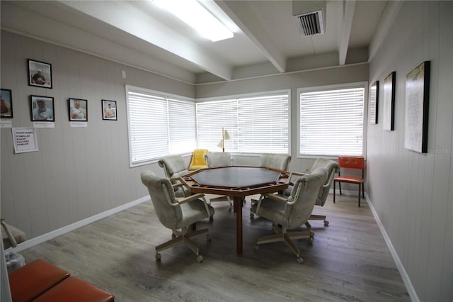 dining space with wood walls, beamed ceiling, and hardwood / wood-style flooring