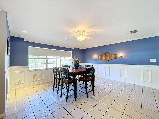 tiled dining area with ceiling fan and crown molding