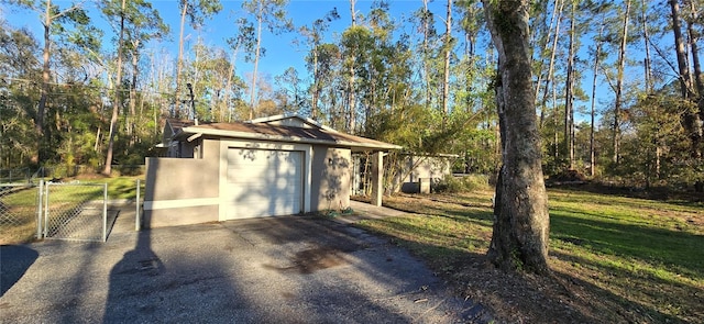 view of outdoor structure with driveway, a gate, and fence