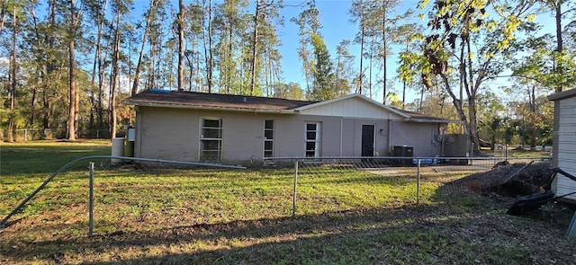 back of property with central AC, a lawn, and fence