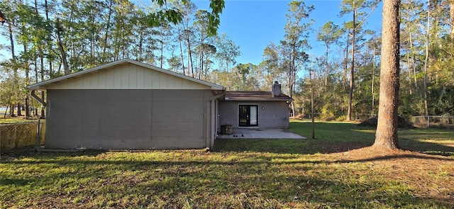 back of property with a patio area, a lawn, a chimney, and fence